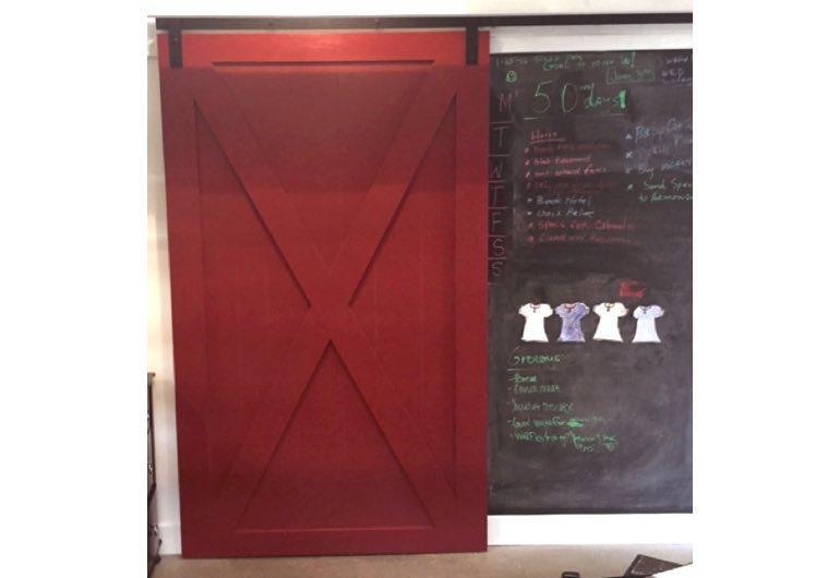 Bright red sliding barn door with black track next to chalkboard 